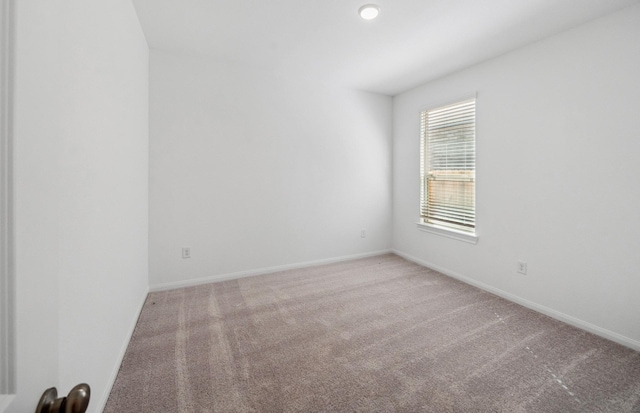 unfurnished room featuring carpet and baseboards