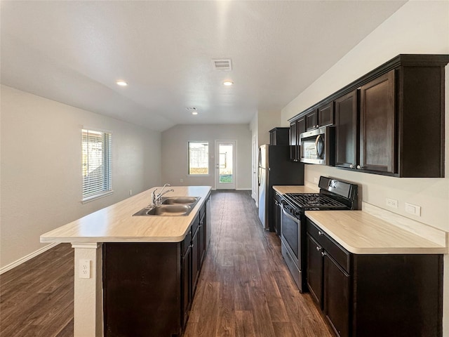 kitchen with sink, dark wood-type flooring, an island with sink, vaulted ceiling, and appliances with stainless steel finishes