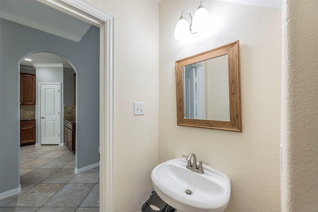 bathroom featuring tile patterned floors, decorative backsplash, sink, and crown molding