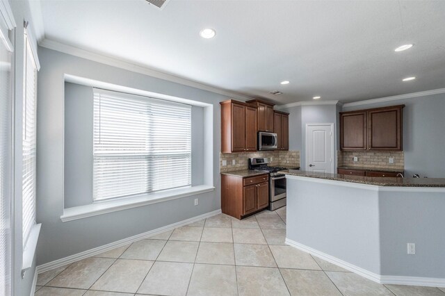 kitchen featuring appliances with stainless steel finishes, backsplash, crown molding, light tile patterned floors, and dark stone countertops