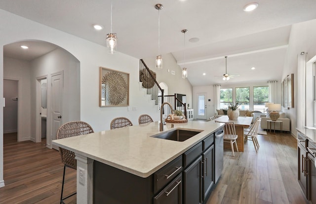 kitchen featuring a breakfast bar, vaulted ceiling, sink, decorative light fixtures, and dark hardwood / wood-style floors