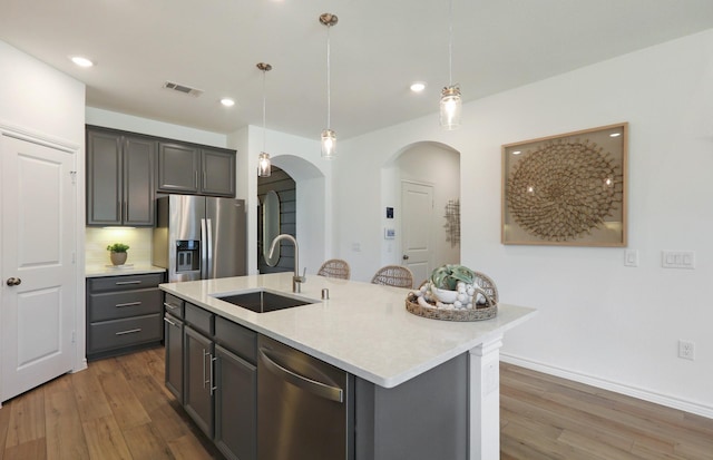 kitchen featuring pendant lighting, a kitchen island with sink, sink, dark hardwood / wood-style floors, and appliances with stainless steel finishes