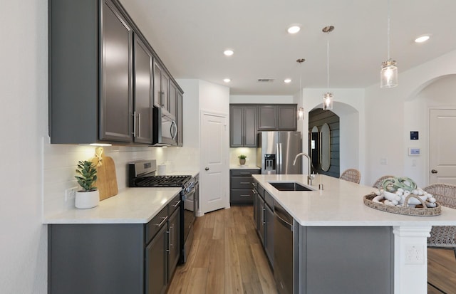 kitchen with pendant lighting, an island with sink, stainless steel appliances, and sink