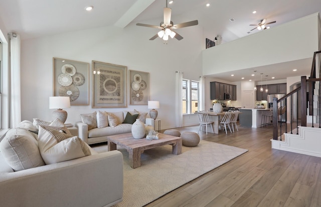 living room featuring ceiling fan, light hardwood / wood-style flooring, high vaulted ceiling, and beamed ceiling