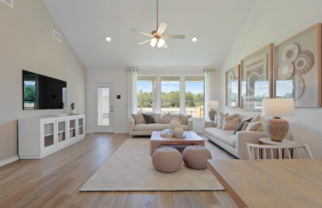 living room with ceiling fan, high vaulted ceiling, and light wood-type flooring