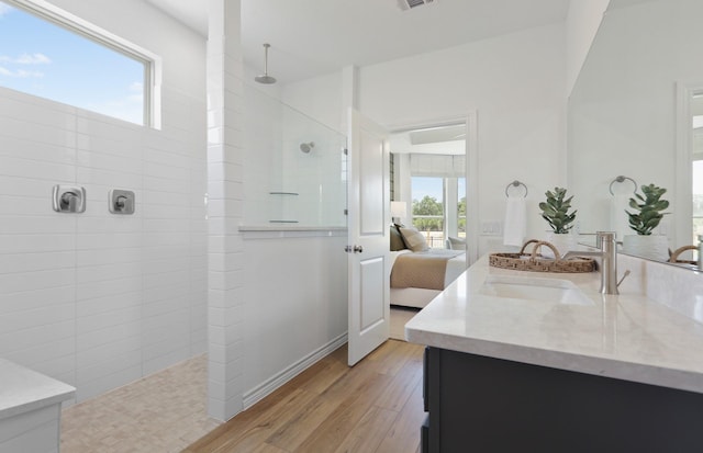 bathroom featuring tiled shower, vanity, a healthy amount of sunlight, and hardwood / wood-style flooring