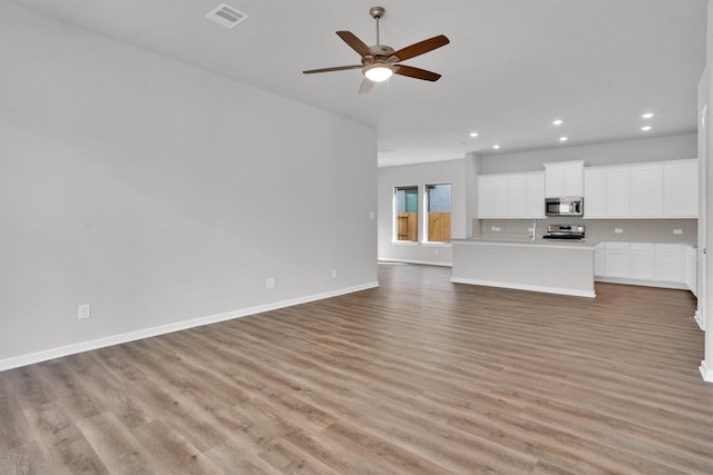 unfurnished living room featuring ceiling fan and light hardwood / wood-style flooring