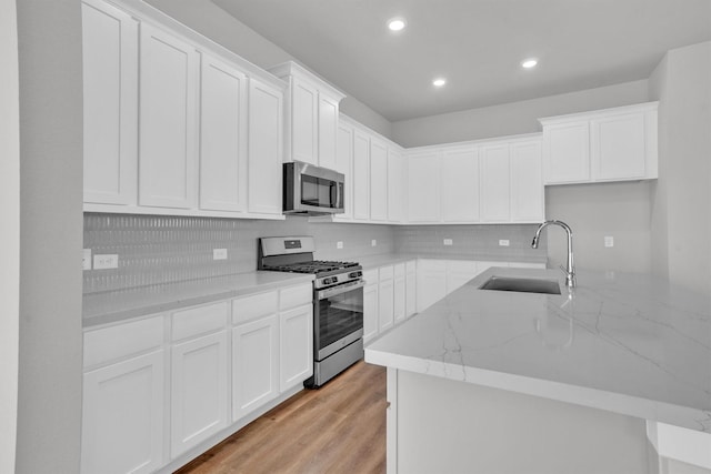 kitchen with white cabinets, light hardwood / wood-style floors, sink, and appliances with stainless steel finishes