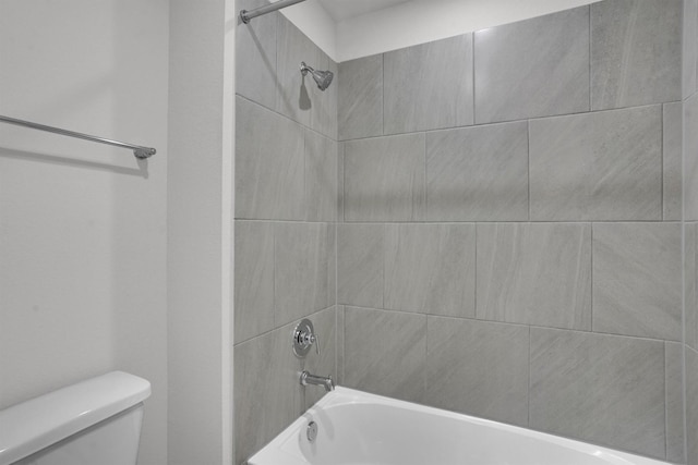 bathroom featuring tiled shower / bath combo and toilet