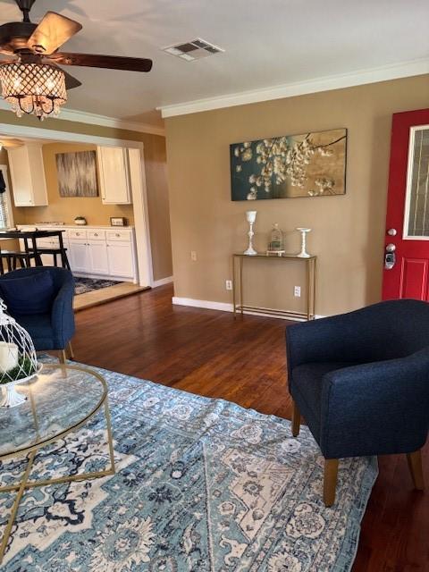 living room featuring dark hardwood / wood-style floors, ceiling fan, and crown molding