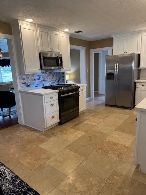 kitchen featuring decorative backsplash, white cabinets, and appliances with stainless steel finishes