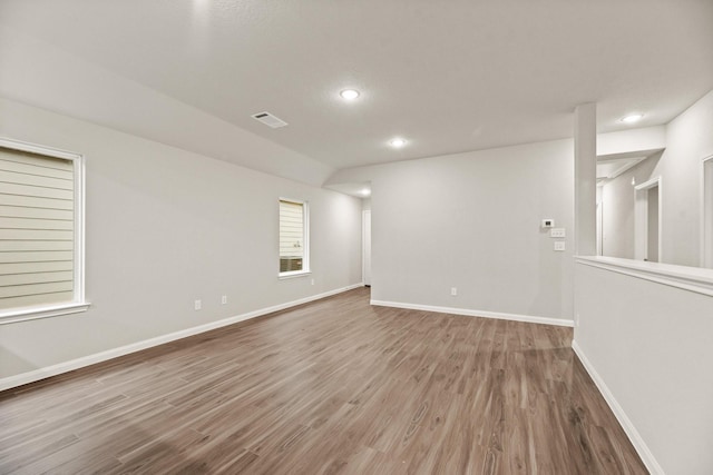 unfurnished room with hardwood / wood-style flooring and lofted ceiling