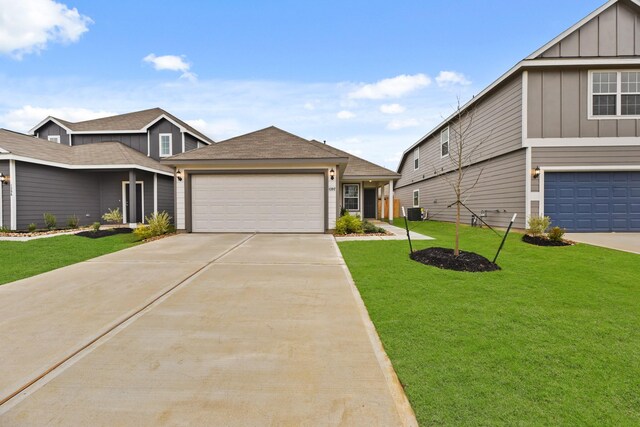 view of front of home with a garage, a front lawn, and central air condition unit