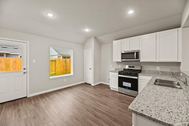 kitchen with light stone countertops, white cabinetry, sink, and stainless steel appliances