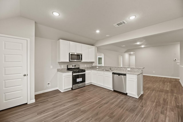 kitchen with lofted ceiling, white cabinets, sink, light stone counters, and stainless steel appliances