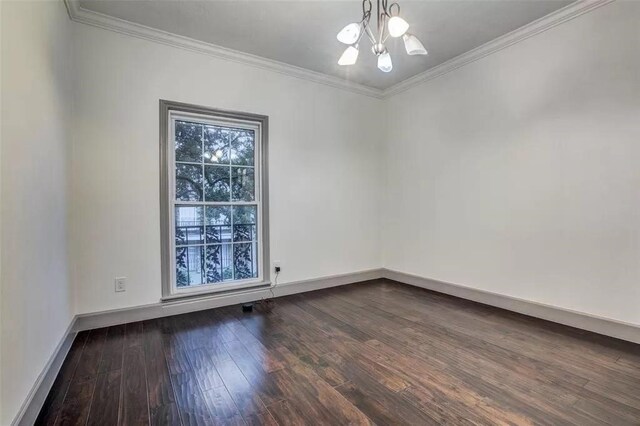 spare room with hardwood / wood-style flooring, ornamental molding, and a notable chandelier