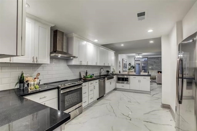 kitchen featuring white cabinets, sink, wall chimney exhaust hood, appliances with stainless steel finishes, and kitchen peninsula