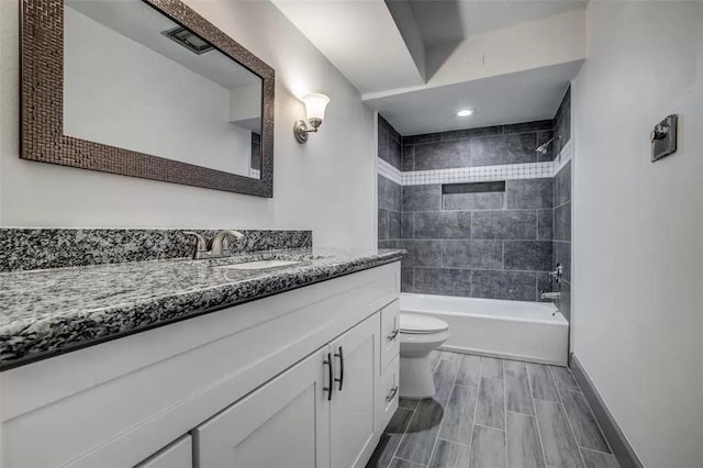 full bathroom with vanity, tiled shower / bath, and toilet