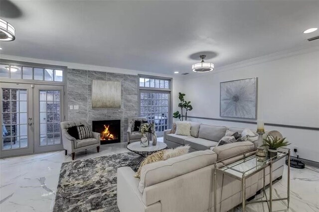 living room featuring crown molding, a fireplace, a healthy amount of sunlight, and french doors