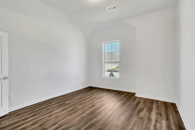 spare room with dark hardwood / wood-style floors and vaulted ceiling