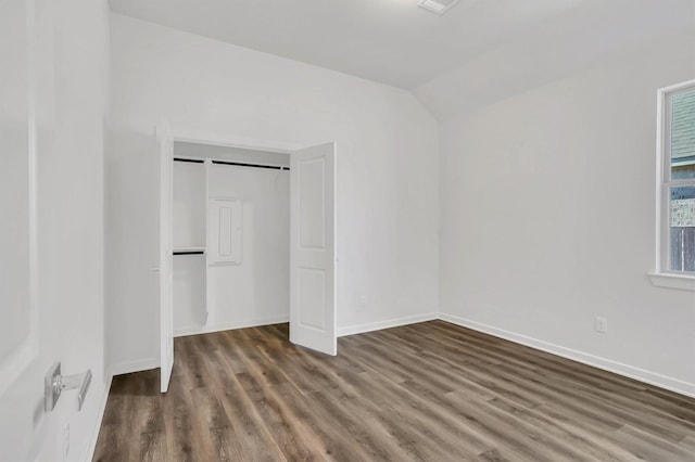 unfurnished bedroom featuring dark hardwood / wood-style flooring, a closet, and vaulted ceiling