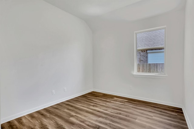 spare room with hardwood / wood-style flooring and lofted ceiling