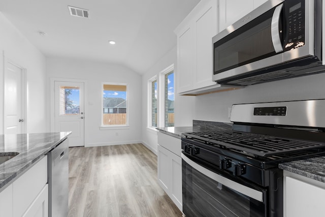 kitchen featuring dark stone countertops, white cabinetry, stainless steel appliances, and light wood-type flooring