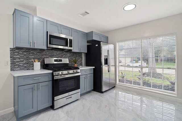 kitchen featuring backsplash, gray cabinetry, and appliances with stainless steel finishes