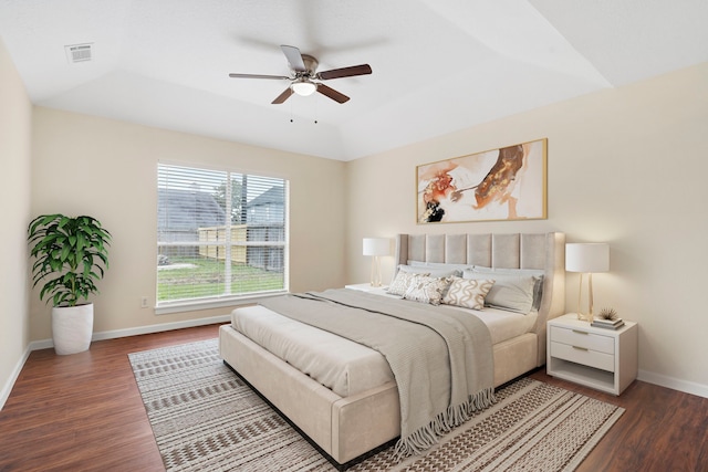 bedroom with ceiling fan, dark hardwood / wood-style floors, and a tray ceiling