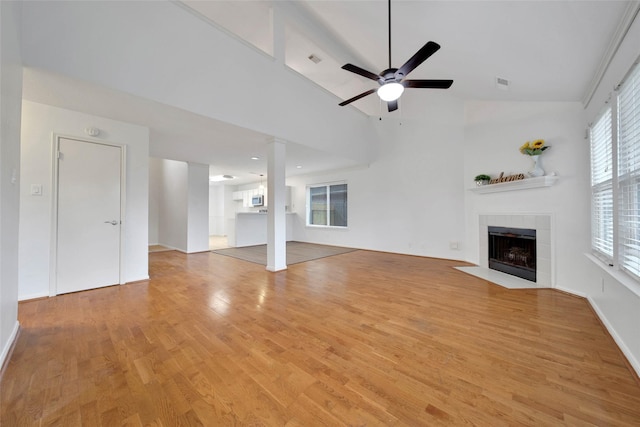 unfurnished living room with ceiling fan, light hardwood / wood-style floors, a fireplace, and high vaulted ceiling