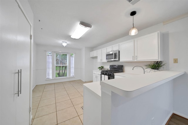 kitchen featuring kitchen peninsula, gas stove, pendant lighting, light tile patterned floors, and white cabinetry