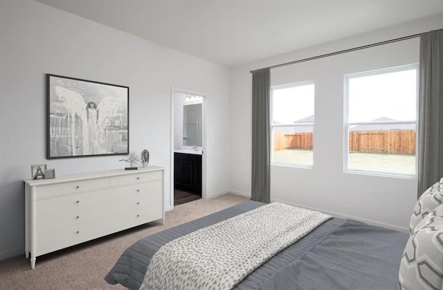 bedroom with sink, light colored carpet, and ensuite bathroom