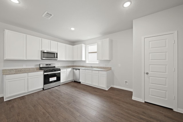 kitchen featuring visible vents, dark wood finished floors, appliances with stainless steel finishes, white cabinetry, and a sink