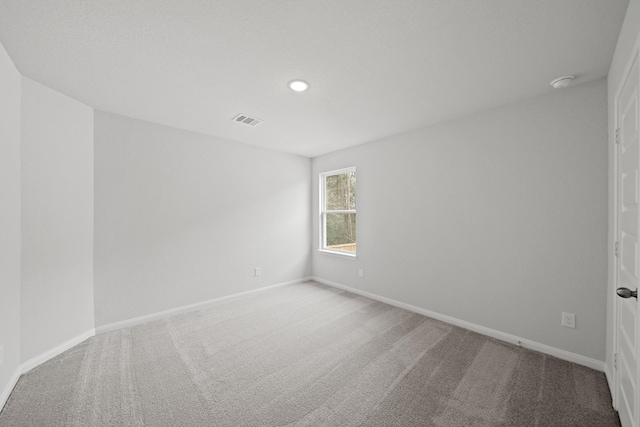 spare room featuring carpet, visible vents, baseboards, and recessed lighting