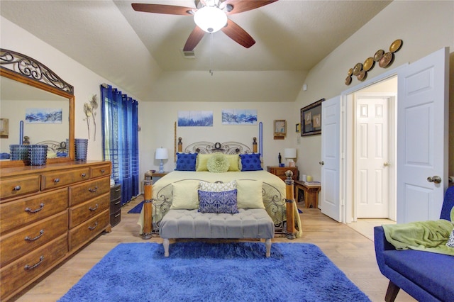 bedroom with ceiling fan, light hardwood / wood-style floors, and vaulted ceiling