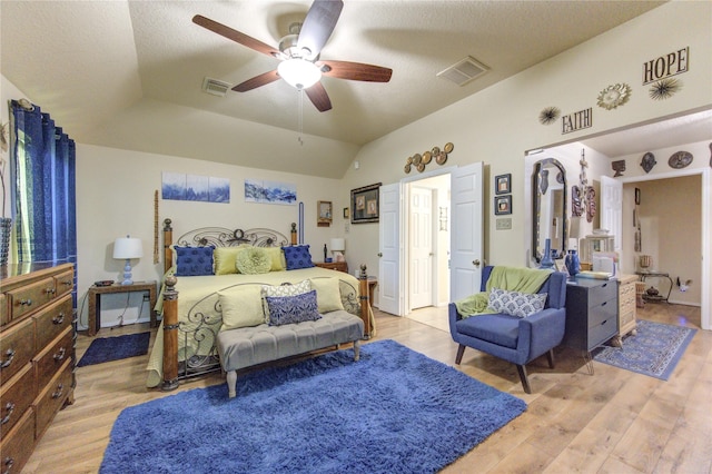 bedroom with a textured ceiling, ceiling fan, vaulted ceiling, and light wood-type flooring