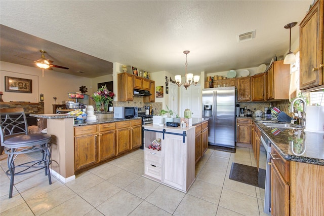 kitchen featuring a kitchen breakfast bar, a center island, hanging light fixtures, and appliances with stainless steel finishes