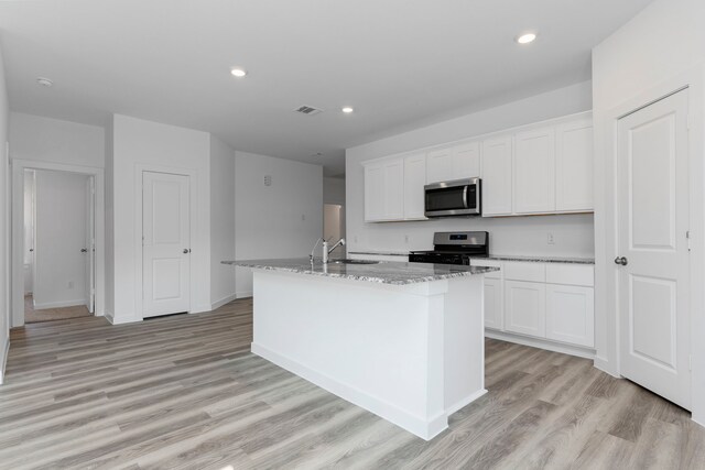 kitchen featuring a center island with sink, black range with gas stovetop, white cabinetry, and sink