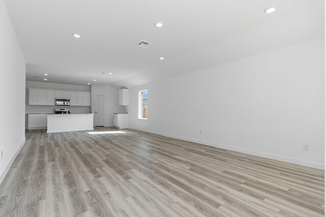 unfurnished living room with vaulted ceiling and light hardwood / wood-style flooring