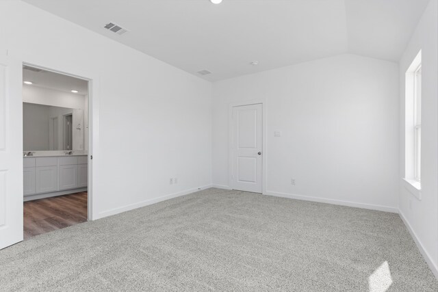 carpeted spare room featuring lofted ceiling