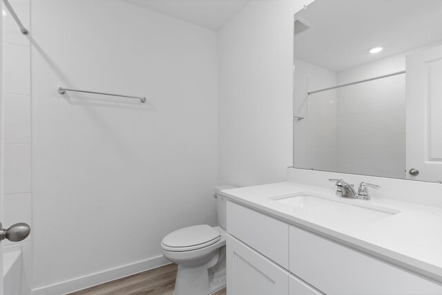 bathroom with a shower, vanity, hardwood / wood-style flooring, and toilet