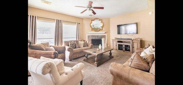 carpeted living room with ceiling fan and a tiled fireplace