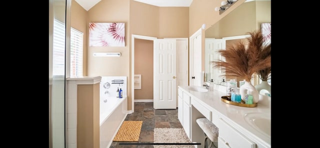 bathroom featuring a bathing tub, vanity, and lofted ceiling