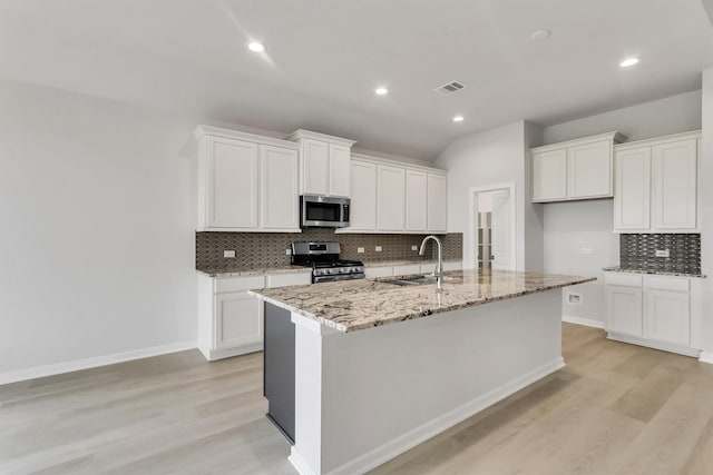 kitchen with white cabinets, stainless steel appliances, a kitchen island with sink, and sink