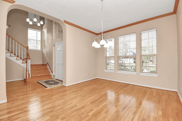 unfurnished dining area featuring a healthy amount of sunlight, wood-type flooring, ornamental molding, and an inviting chandelier