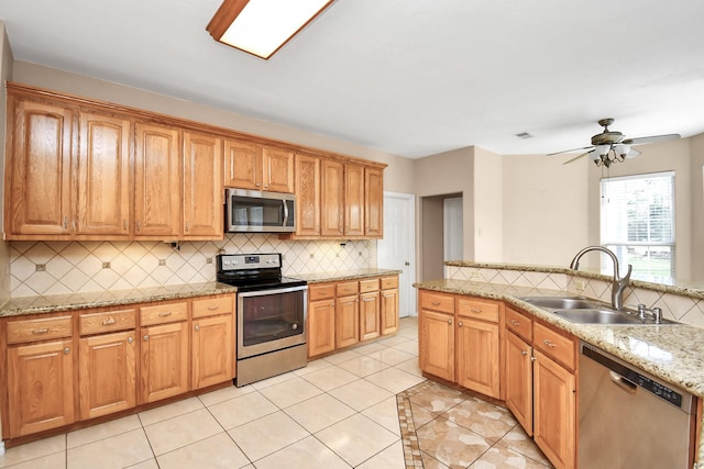 kitchen with sink, ceiling fan, light tile patterned floors, appliances with stainless steel finishes, and tasteful backsplash