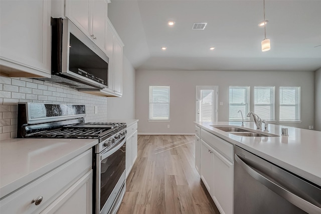 kitchen featuring backsplash, white cabinetry, light hardwood / wood-style flooring, and stainless steel appliances