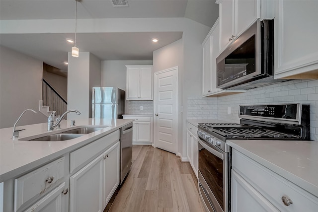 kitchen featuring backsplash, sink, light wood-type flooring, white cabinetry, and stainless steel appliances