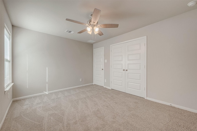 unfurnished bedroom featuring ceiling fan, a closet, and light colored carpet