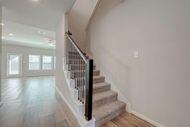 stairway with ceiling fan and wood-type flooring